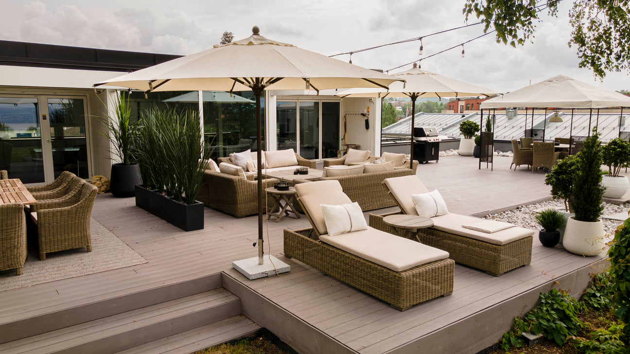 Bilde av moderne parasoll med stabil parasollfot på terrasse, omgitt av hagemøbler – gir skygge og solbeskyttelse for uteplassen.